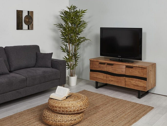 Meuble TV industriel en bois et métal noir, avec canapé gris et plante en arrière-plan